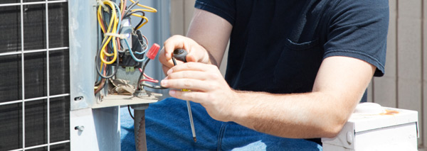 HVAC technician repairing an outdoor AC unit